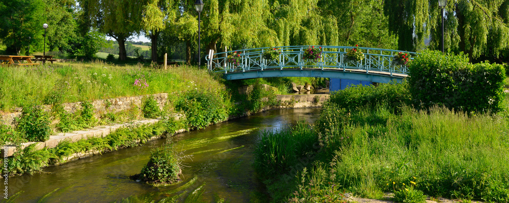 Panoramique La Loisance traversée par un pont fleuri, coule dans un parc de verdure à Antrain (35560 Val-Couesnon), département d'Île-et-Vilaine en région Bretagne, France