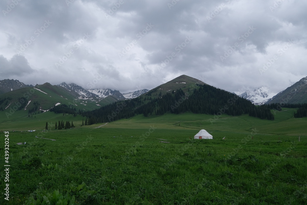 mongolian yurt at green prairie in Xinjiang China. Snow mountains behind mongolian yurt at green prairie in Xinjiang China. Snow mountains behind