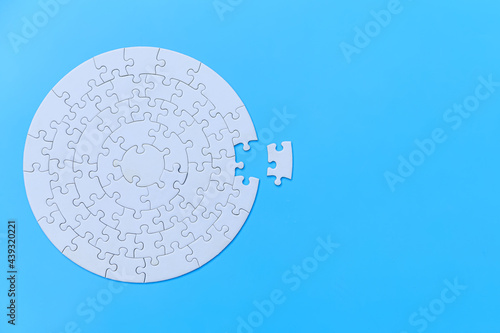 White jigsaw puzzle on a blue background. Completing final task, missing jigsaw puzzle pieces and business concept with a puzzle piece missing. photo