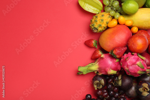 Many different delicious exotic fruits on red background  flat lay. Space for text