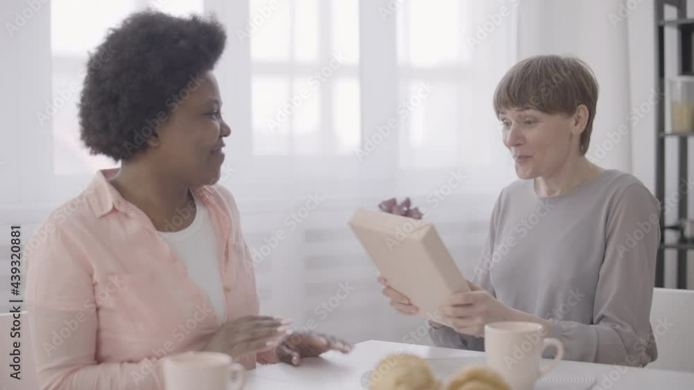 African woman presenting gift to best friend, birthday surprise, friendship African woman presenting gift to best friend, birthday surprise, friendship