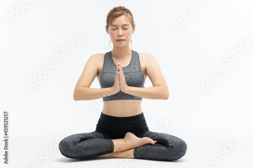 Beautiful Asian woman practicing yoga on a yoga mat against a white background.