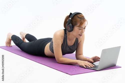 Beautiful Asian woman practicing yoga on a yoga mat against a white background.