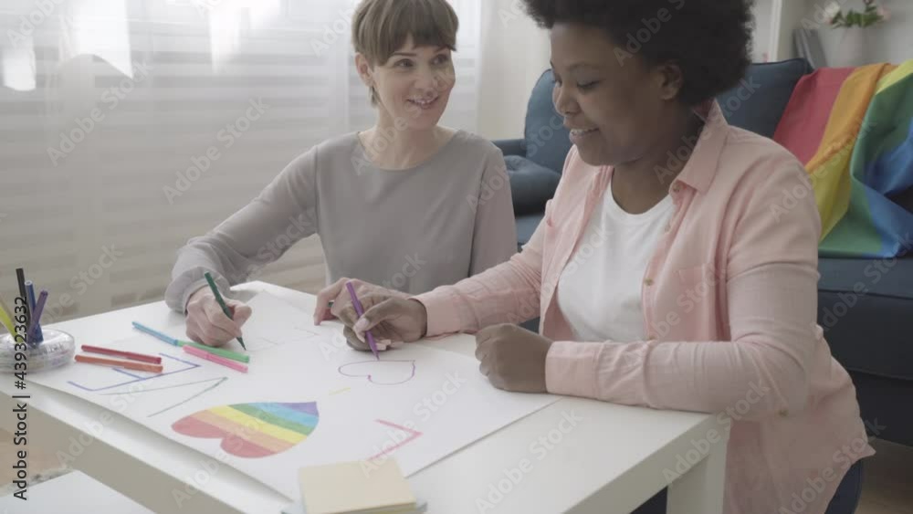 Multiethnic female couple painting placards for lgbt pride parade, human rights Multiethnic female couple painting placards for lgbt pride parade, human rights
