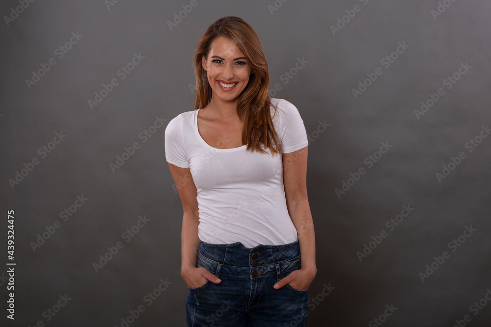 Cheerful brunette model dressed in casual clothes shows smile and happy emotions isolated on gray background
