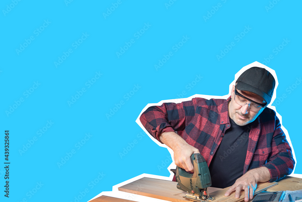 Carpenter on blue background. Carpenter works with electric jigsaw. Electric jigsaw in hands of man furniture maker. Man is engaged in woodworking. Place for inscription about work as furniture maker Carpenter on blue background. Carpenter works with electric jigsaw. Electric jigsaw in hands of man furniture maker. Man is engaged in woodworking. Place for inscription about work as furniture maker