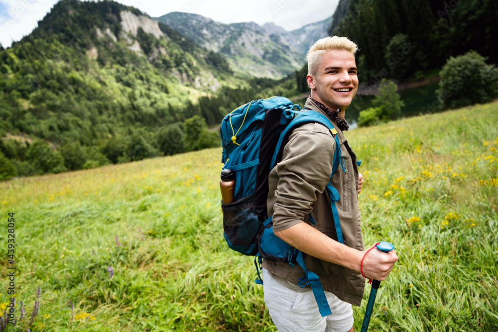 Hiker young man with backpack and trekking poles looking at the mountains in outdoor Hiker young man with backpack and trekking poles looking at the mountains in outdoor