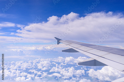 View of airplane wing with blue sky and cloud.