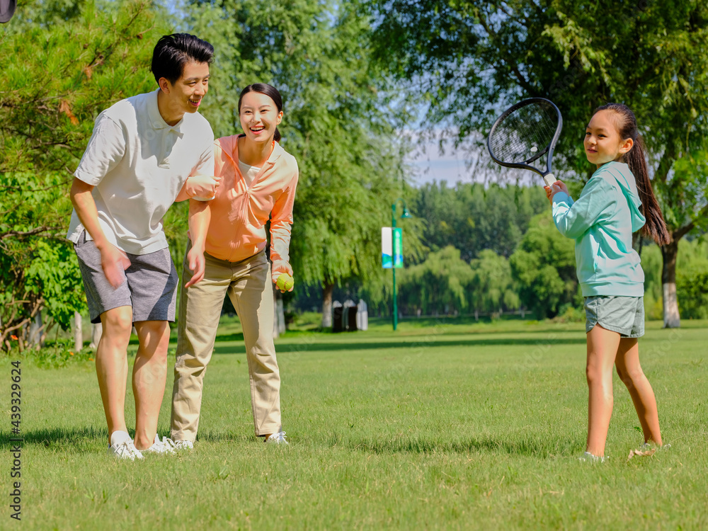 Happy family of three playing tennis in the park Happy family of three playing tennis in the park
