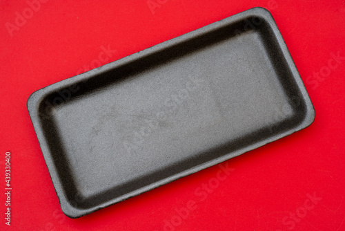 Styrofoam food tray on red background.