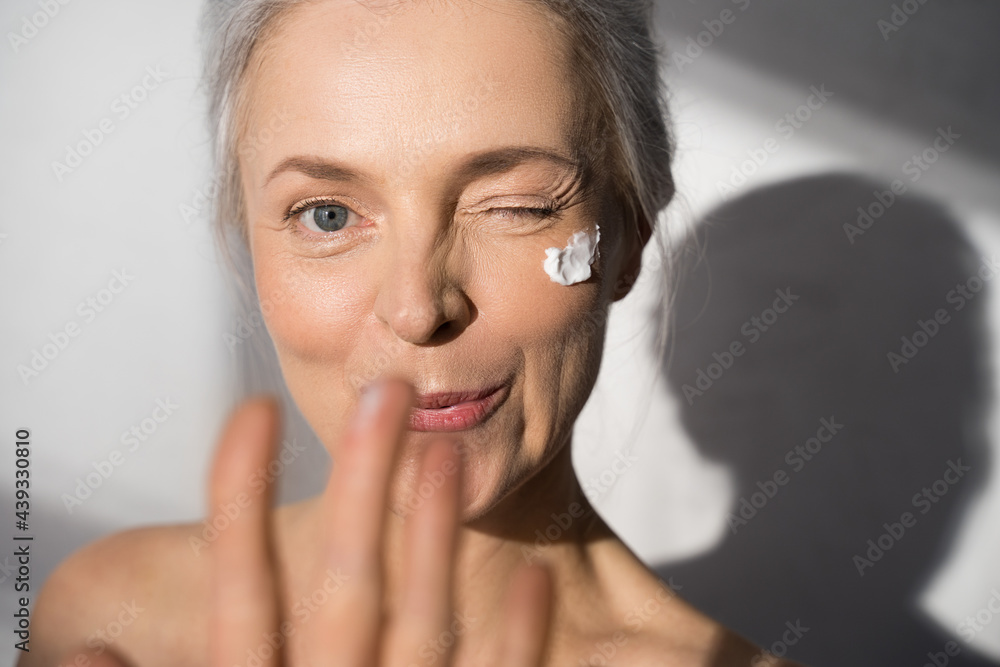 Woman with protective skin care cream and moisturizer lotion on her happy smiling face - obrazy, fototapety, plakaty 