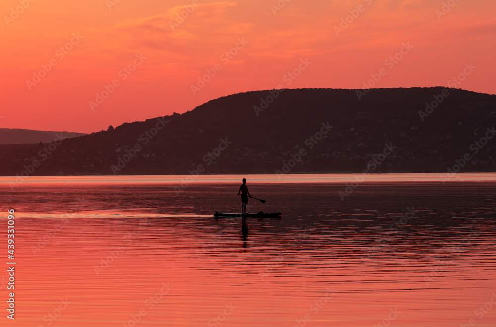 landscape with a man paddling on a raft in the evening at Lake Balaton - Hungary 