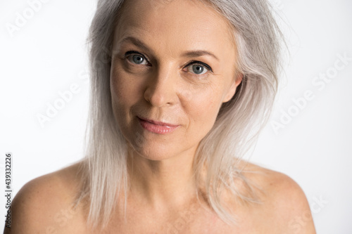 Woman with grey hair and bare shoulders looking thoughtfully at the camera photo