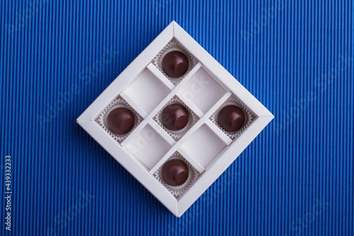 Five brown chocolate candies in the box on blue background. photo