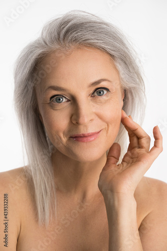 Obraz na plátně Woman with grey hair holding hands near her face and smiling