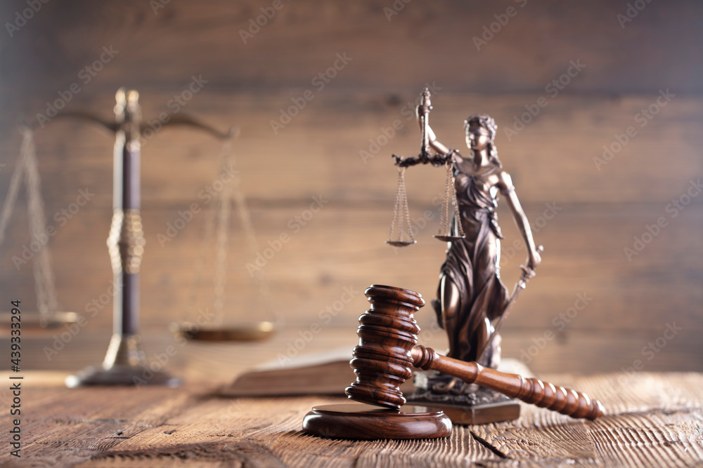 Law theme. Judge chamber. Judge’s gavel, scale, Themis sculpture on the brown rustic desk and the brown background.