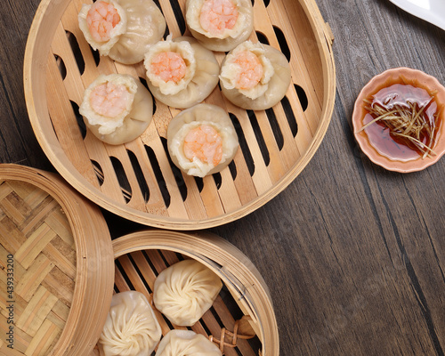 Prawn shrimp shaomai Xiao long bao dim sum dumpling chicken prawn fish seafood vegetable in bamboo steamer sauce chopsticks on rustic background photo