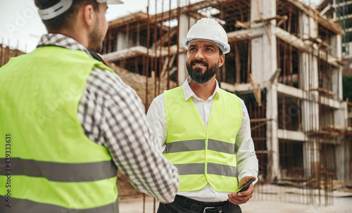 Business partners shaking hands on construction site photo