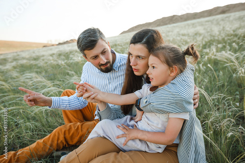 A hipster family walks in a summer field.