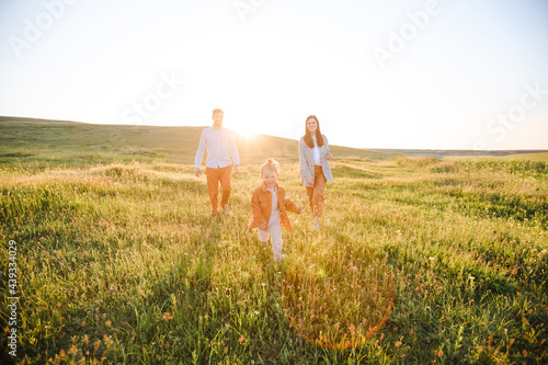 A hipster family walks in a summer field.