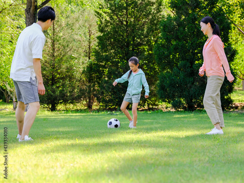 Happy family of three playing football in the park