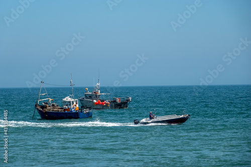 speed boat passing fishing trawlers in the sea