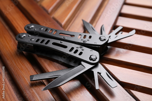 Modern compact portable multitool on wooden table, closeup