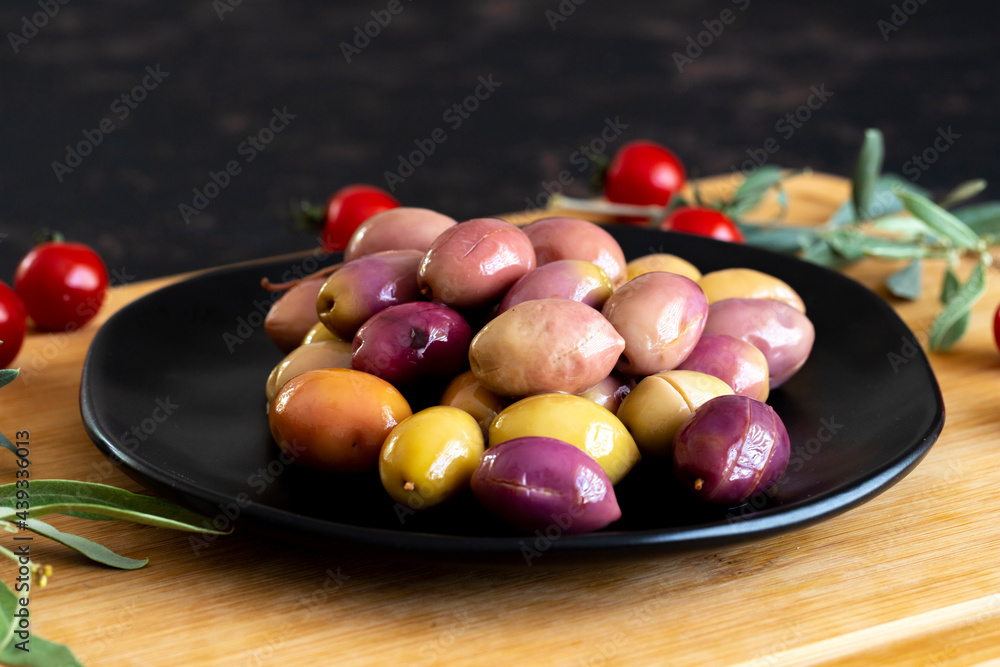 Mixed marinated olives (green and purple). Tasty colored olives in the plate. Mixed marinated olives (green and purple). Tasty colored olives in the plate.