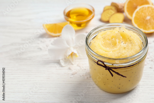 Body scrub in glass jar on white wooden table  closeup. Space for text