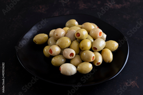 Green olives stuffed with peppers on a dark background. Tasty green olives in the plate.