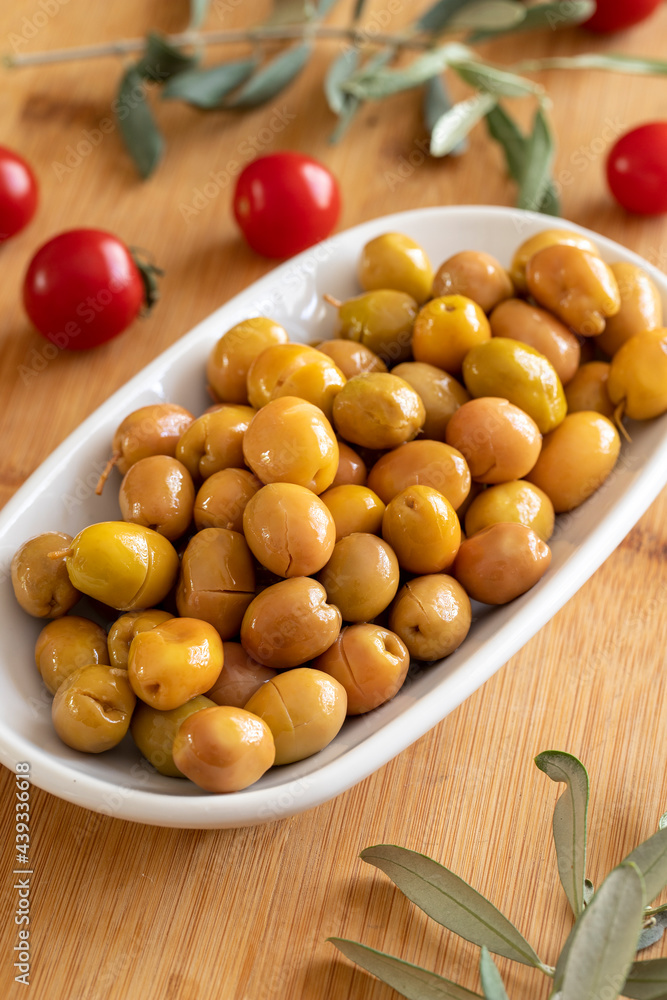 Scratched olive. Tasty organic scratched yellow olives in the plate. Olives on wooden background Scratched olive. Tasty organic scratched yellow olives in the plate. Olives on wooden background
