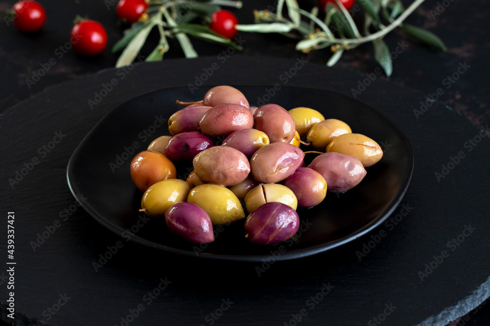 Mixed marinated olives (green and purple) on dark background. Tasty colored olives in the plate Mixed marinated olives (green and purple) on dark background. Tasty colored olives in the plate