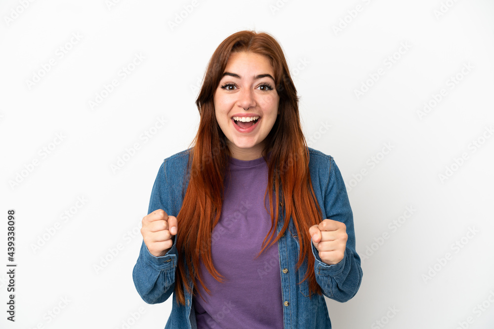 Young redhead woman isolated on white background celebrating a victory in winner position Young redhead woman isolated on white background celebrating a victory in winner position