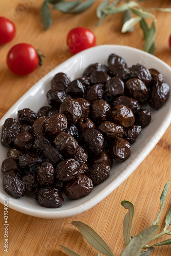 Black olive. Tasty organic black olives in the plate. Olives on wooden background
