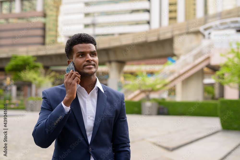 Portrait of African businessman outdoors in city using mobile phone Portrait of African businessman outdoors in city using mobile phone