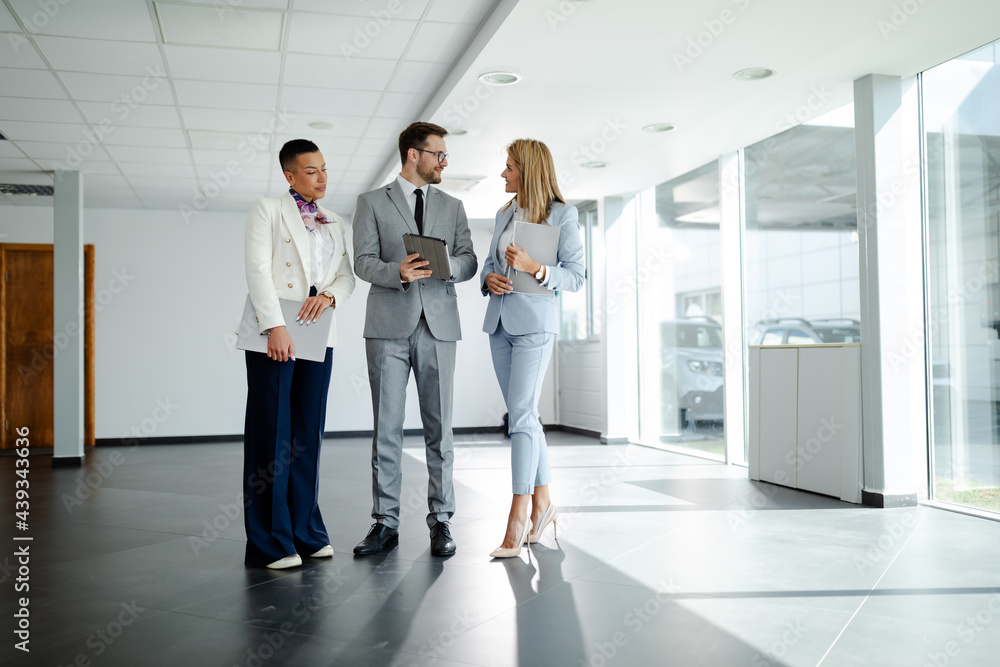 Three business colleagues discussing work related matters on an office building hallway. Team work. Three business colleagues discussing work related matters on an office building hallway. Team work.