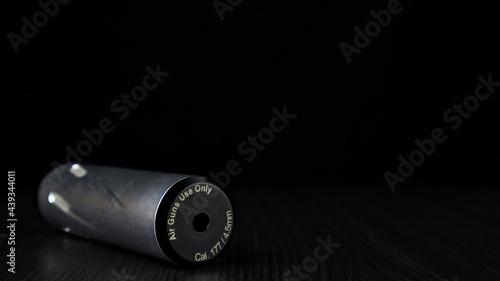 Airgun silincer suppressor colored silver with aluminum on a black background © Vins Contributor