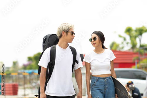 Asian young couple or friends man and woman playing surfskate or skate board in urban city outdoor. Extream sports