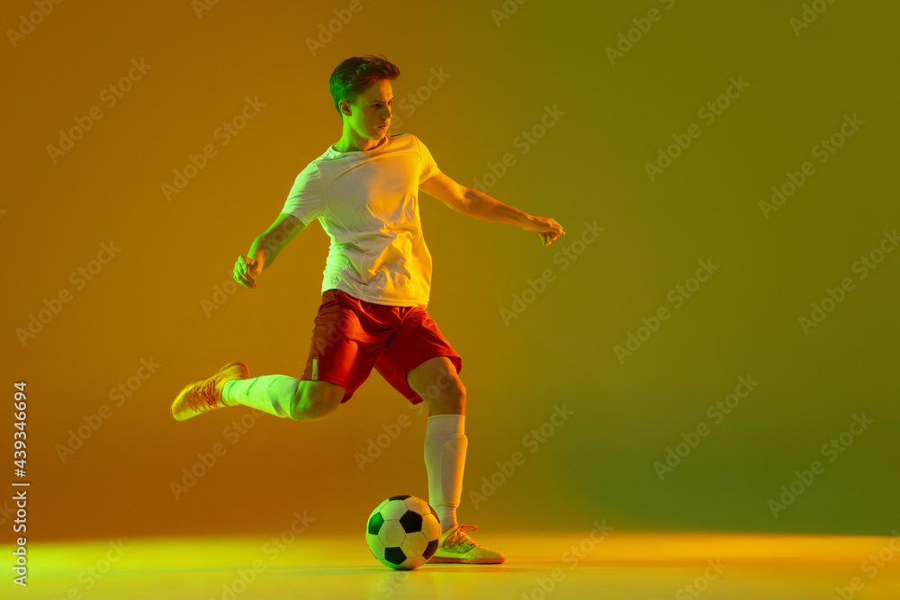 One male soccer football player in action and motion isolated on gradient green yellow background in neon light