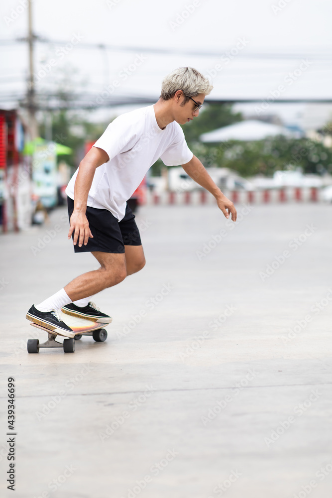 Fototapeta premium Asian young man playing surfskate or skate board in gas station urban city outdoor. Extream sports