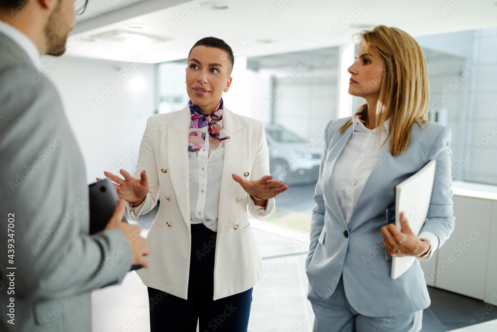Young business professionals standing together and having casual discussing in office hallway. Young business professionals standing together and having casual discussing in office hallway.