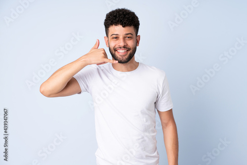 Young Moroccan man isolated on blue background making phone gesture. Call me back sign