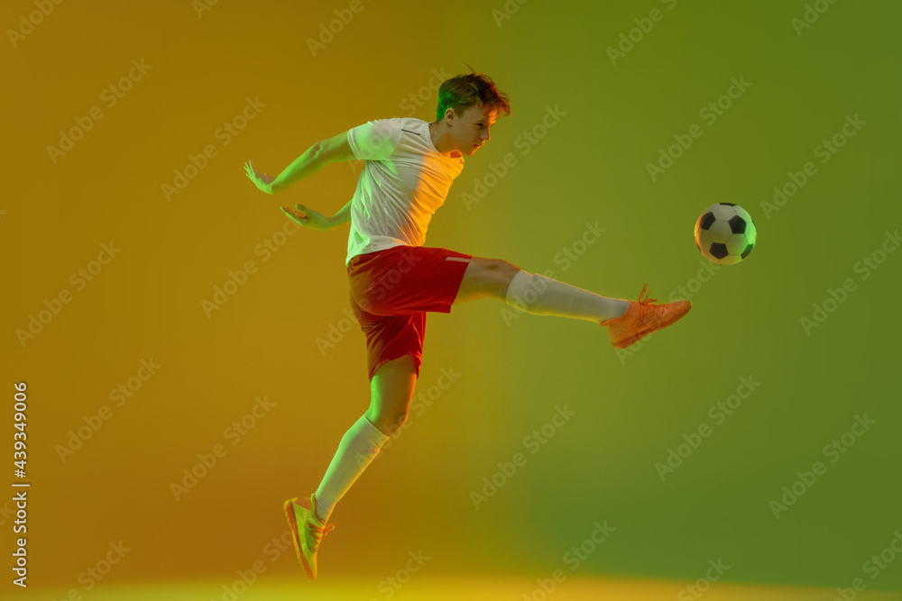 One male soccer football player in action and motion isolated on gradient green yellow background in neon light