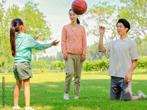 Happy family of three playing basketball in the park
