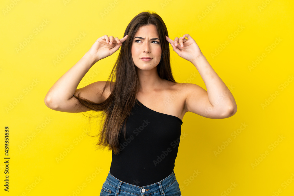 Young Brazilian woman isolated on yellow background having doubts and thinking Young Brazilian woman isolated on yellow background having doubts and thinking