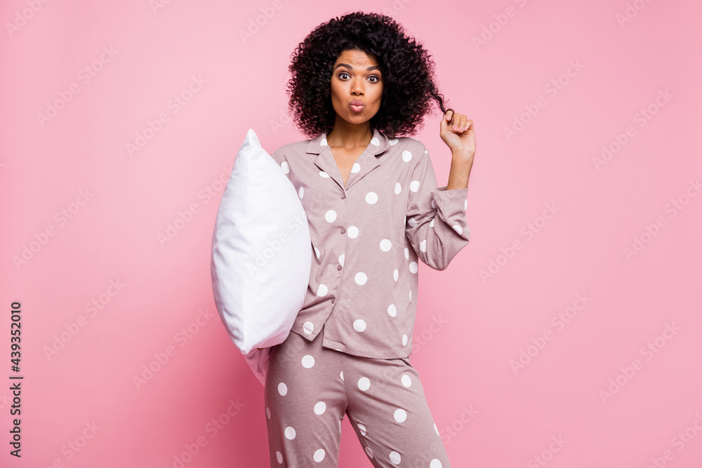 Photo of cute flirty curly dark skin woman dotted nightwear holding white pillow sending kiss isolated pink color background Photo of cute flirty curly dark skin woman dotted nightwear holding white pillow sending kiss isolated pink color background