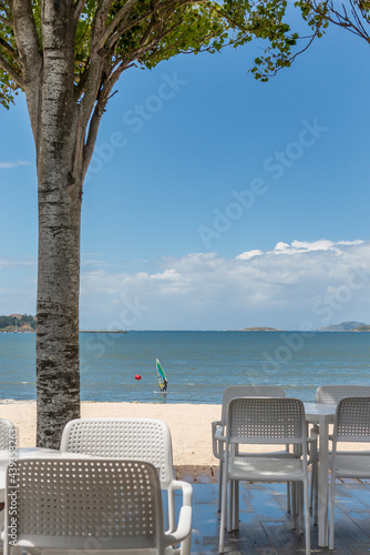 Beach bar terrace in the shade of the trees with a surfer zigzagging © Toyakisfoto.photos