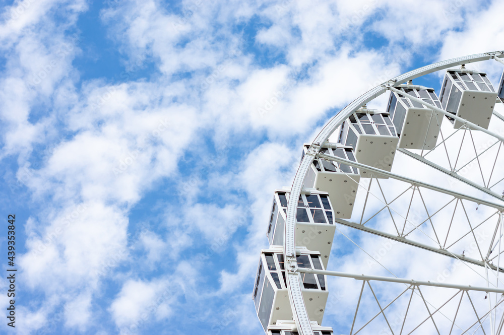 Ferris wheel in a sunny day with white clouds