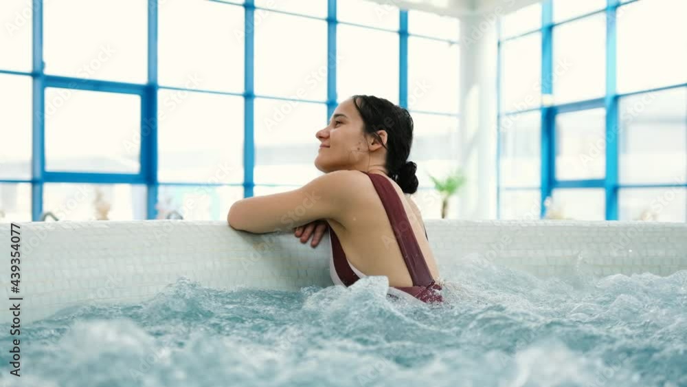 Attractive young woman having hydrotherapy in a luxurious pool. Portrait of sexy girl enjoying spa jacuzzi in slow motion. Attractive young woman having hydrotherapy in a luxurious pool. Portrait of sexy girl enjoying spa jacuzzi in slow motion.