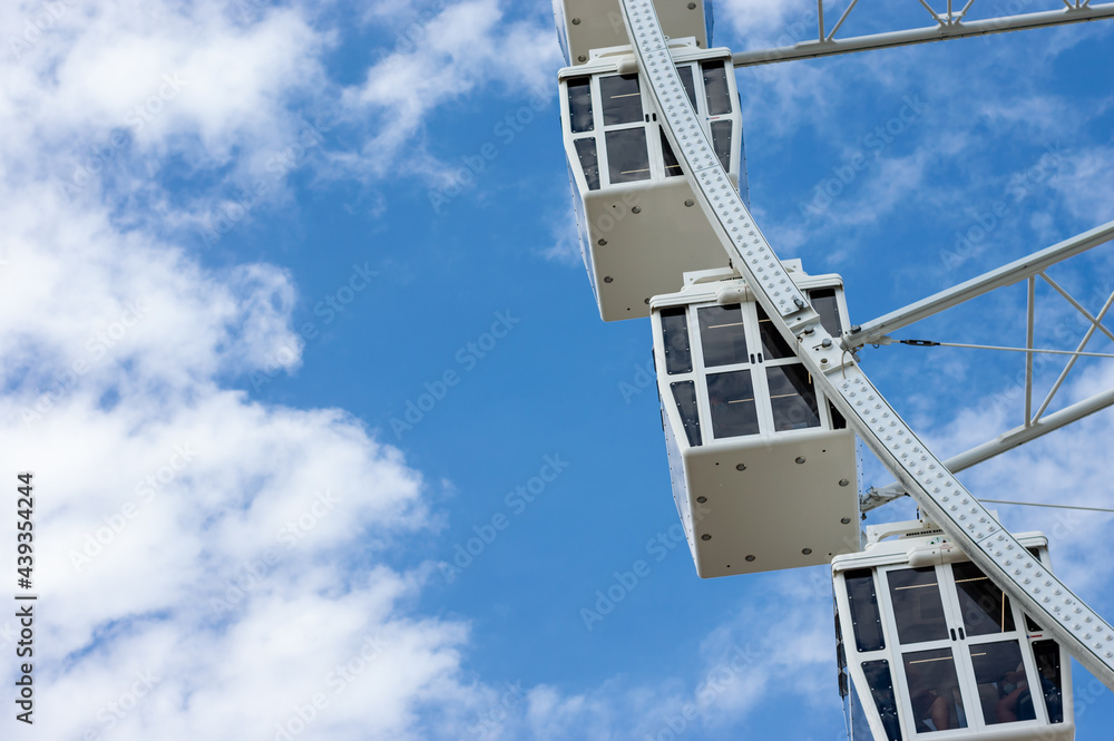 Ferris wheel cabins in a sunny day with white clouds